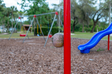 Multiple plastic and rubber swings hanging from chains in a children's park. There's a blue plastic...