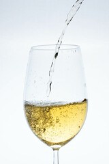 white wine glass pouring the liquid on a light background