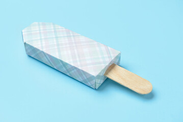 Ice cream in package and stick on blue background, closeup