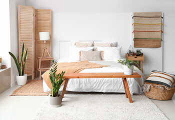 Interior of light bedroom with bed, florariums and houseplants