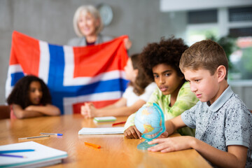 children listen with interest to teacher, who talks about geographical location of Norway