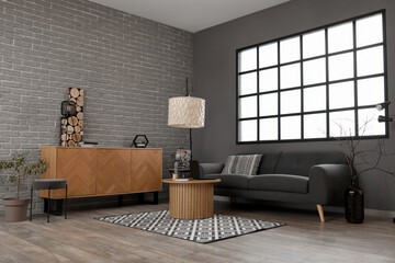 Interior of stylish living room with black sofa and modern laptop on coffee table