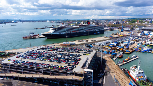 Queen Victoria cruise ship moored in the Port of Southampton on the Channel coast in southern England, United Kingdom - Parking full of new cars just unloaded from a Ro-Ro ship