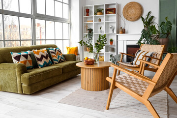 Interior of bright living room with cozy sofa, armchairs and coffee table near big window