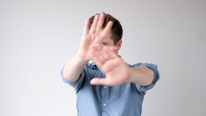European young man shows a stop sign with his hands