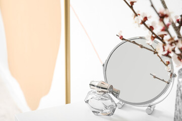 Mirror with perfume on table in room, closeup