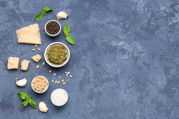 Composition with bowl of delicious pesto sauce and ingredients on blue table