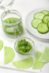 Cotton under-eye patches with cucumber slices on white table, closeup