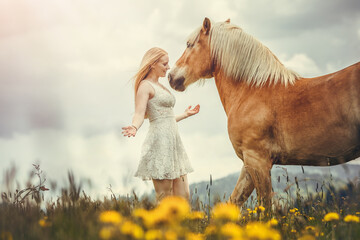 A young woman enjoying time with her haflinger horse in spring outdoors. Female equestrian...