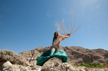 Photography of a beautiful wild woman holding a branch up in the wind.  - 601224891
