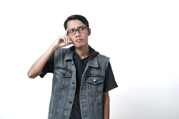 Asian man wearing sleeveless blue jean jacket, thinking gesture. Isolated white background