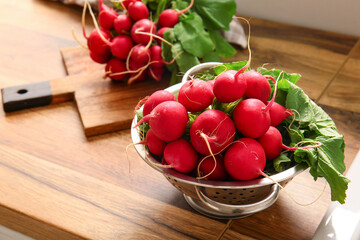 Colander with fresh radish on table