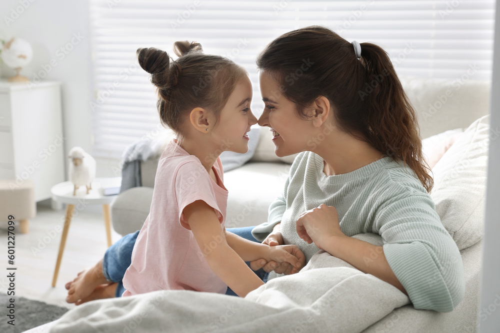 Wall mural Young mother and her daughter spending time together on sofa at home