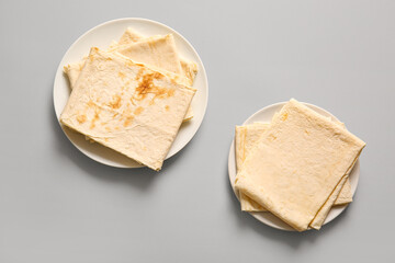 Plates with fresh thin lavash on grey background
