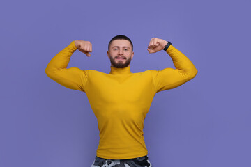Naklejka premium Handsome man showing muscles on purple background