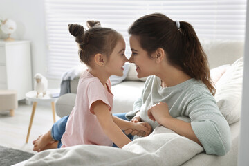 Young mother and her daughter spending time together on sofa at home