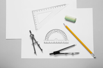 Different rulers, pencil and compasses on light grey background, flat lay