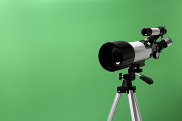 Tripod with modern telescope on green background, closeup. Space for text