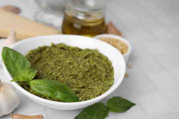 Bowl with tasty pesto sauce and fresh basil on white table, closeup. Space for text