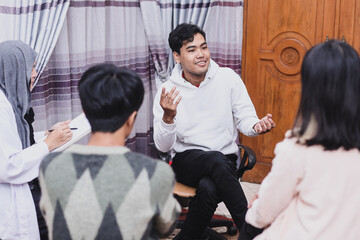 Young man telling a story while other listening at group counseling therapy session. 
