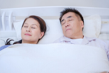 寝室で寝るシニア夫婦