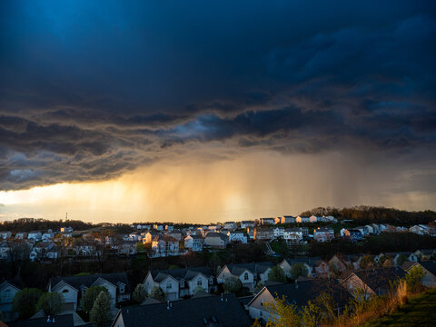 Dramatic clouds and bad weather approaching over US neighborhood with sun-rays.