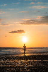 Silhouette of a woman walking towards the sunset on a beach in Costa Rica.