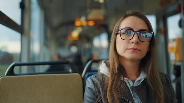 Public transport. Woman in glasses riding a tram in the city, slow motion