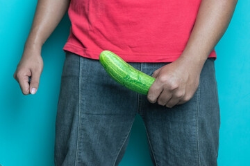 man hand holding cucumber. concept of man erection or hard penis isolated blue background - obrazy, fototapety, plakaty