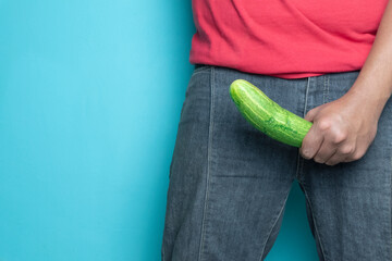man hand holding cucumber. concept of man erection or hard penis isolated blue background