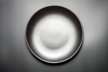 Top view of empty black plate on black background