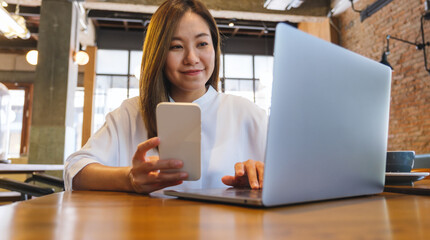 Portrait image of a young woman chatting on mobile phone and laptop computer