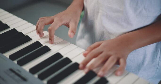 Close-up hand of Creative asian boy with artistic skills taking music lessons online during a video call and playing the piano at home. Music, hobby and lifestyle concepts.