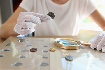 Woman numismatist examining coin with magnifier