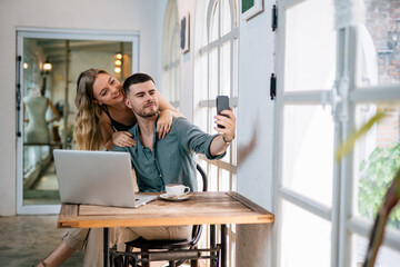 Happy couple taking selfie while choosing project on laptop. People and modern tech concept.