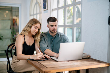 Young couple moving in new home. Sitting and relaxing after unpacking. Searching home decorating ideas on laptop. The concept of couples sharing one idea together.