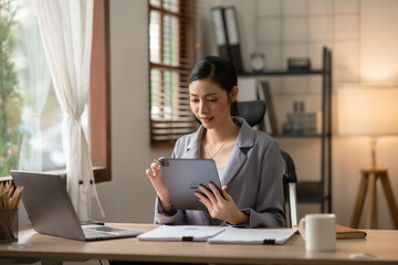 Young Asian businesswoman reading graphs and talking on phone with customers in office