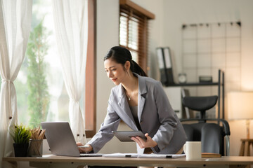 Obraz premium Young Asian businesswoman reading graphs and talking on phone with customers in office