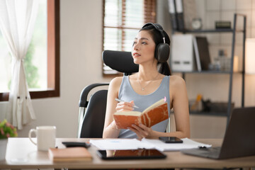 Fototapeta premium Young Asian businesswoman reading graphs and talking on phone with customers in office