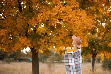 autumn woman in a green dress, brown hat, plaid, against the background of an autumn tree