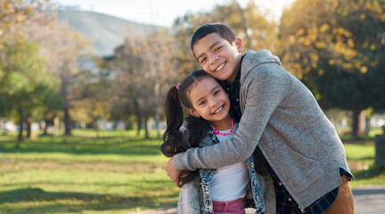 Park, hug and portrait of brother and sister enjoying summer day for bonding, quality time and playing. Family, children and happy siblings hugging, embrace and loving in nature for relaxing together