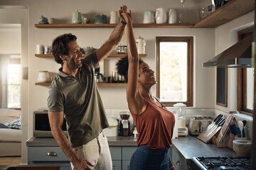 Interracial couple, happy and dance in kitchen for fun bonding, love or holiday together at home....