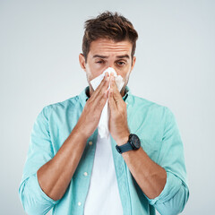 Sick, tissue and portrait of man blowing nose in studio with flu, illness and virus on white background. Health, wellness and face of male person with hayfever, cold symptoms and sneeze for allergy