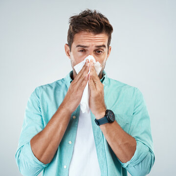 Sick, tissue and portrait of man blowing nose in studio with flu, illness and virus on white background. Health, wellness and face of male person with hayfever, cold symptoms and sneeze for allergy