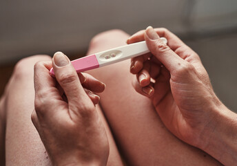 Pregnancy test, hands and woman with pregnant results in her home, apartment or house with positive...