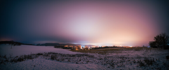 night landscape of a snowy field and a city  with lights on the horizon