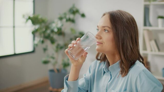 Female Office Worker Drink a Glass of Clean Water. A Smiling Woman Start New Day with a Healthy Life Habit, Holding a Glass Drinking Clean Mineral Natural Water. Lifestyle Healthcare Concept.