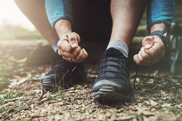 Tying laces, hiking and hands in nature to start walking, adventure or trekking for exercise. Shoes, sports and feet of a man getting ready for cardio, training or a walk for fitness in a park - obrazy, fototapety, plakaty