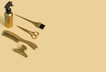 Gold hairdressing tools on a beige background. Template with hair salon accessories and space for text, top view.