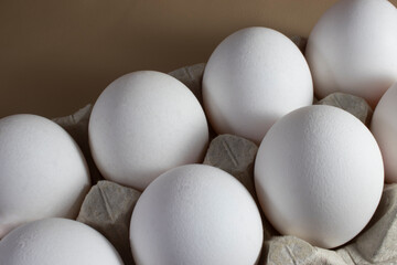 Tray of white fresh eggs close-up on a cardboard form.